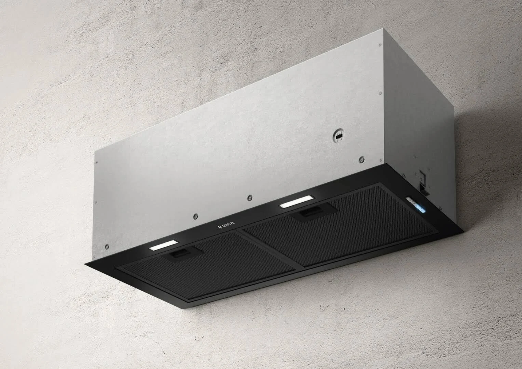 Nowoczesny okap kuchenny jest zamontowany na teksturowanej ścianie. Ma srebrny korpus i czarny spód ze światłami.