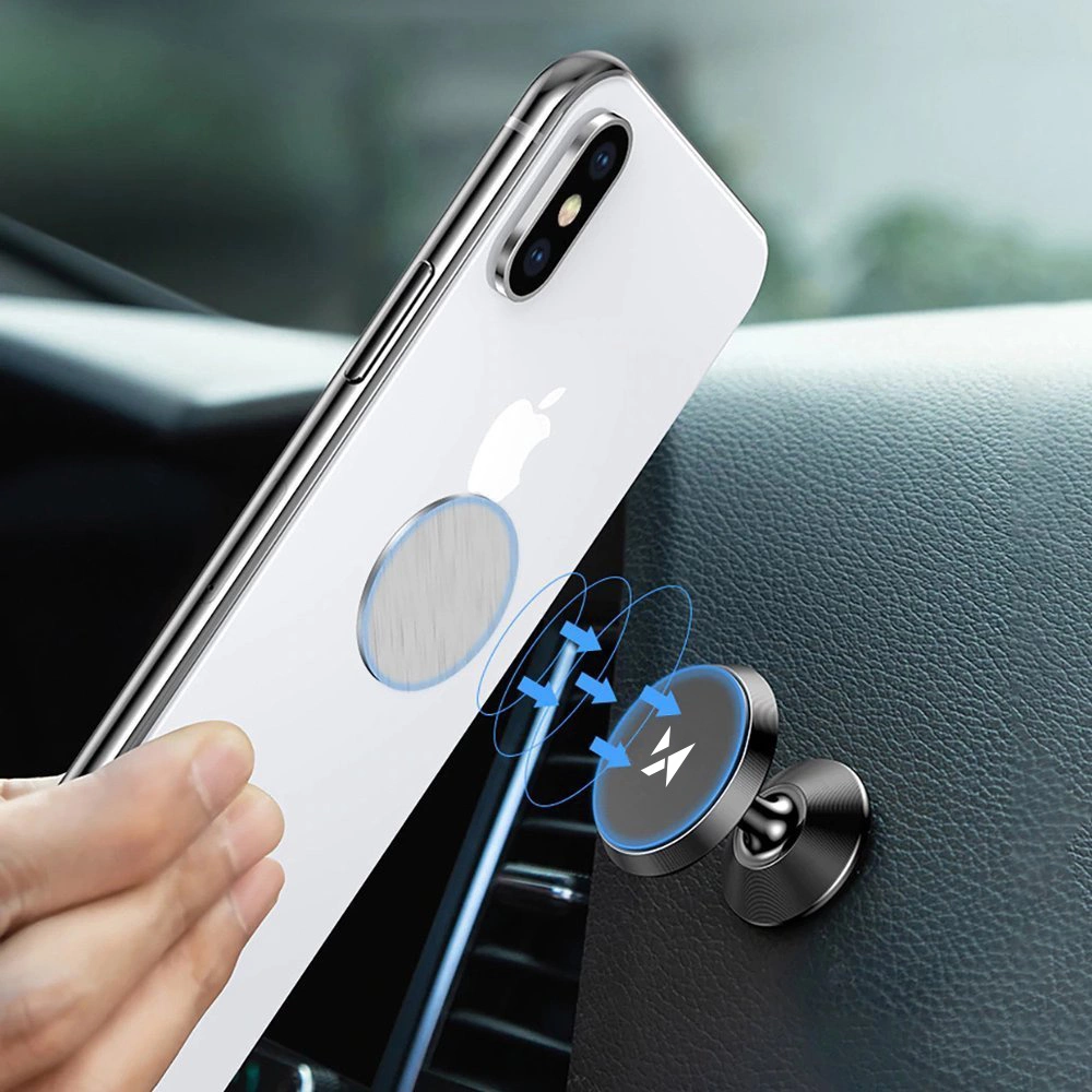 Biały iPhone jest trzymany przez dłoń obok uchwytu do telefonu w samochodzie. Uchwyt jest czarny i ma niebieskie strzałki.