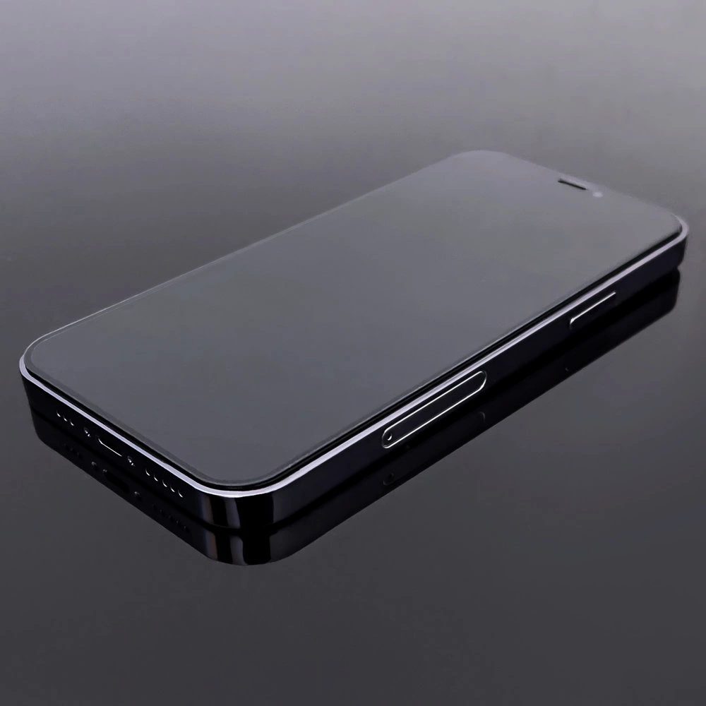 Un primo piano di uno smartphone nero su una superficie riflettente. Il telefono è scuro con un bordo argentato, che riflette la superficie.