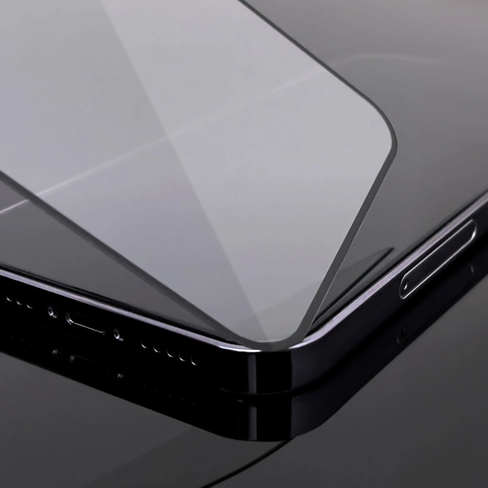 Primo piano di uno smartphone nero con protezione schermo in vetro applicata. Superficie riflettente su sfondo nero.