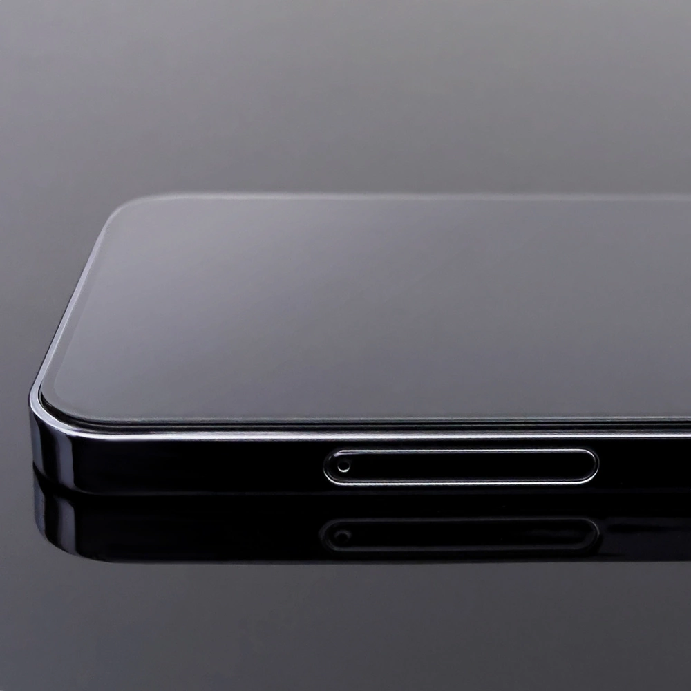 Primo piano di uno smartphone nero. Lo schermo è lucido e riflette l'ambiente. Una cornice metallica lucida circonda il telefono.