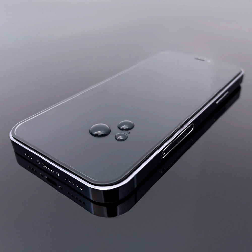 Uno smartphone nero con gocce d'acqua sullo schermo. Il telefono è appoggiato su una superficie riflettente.