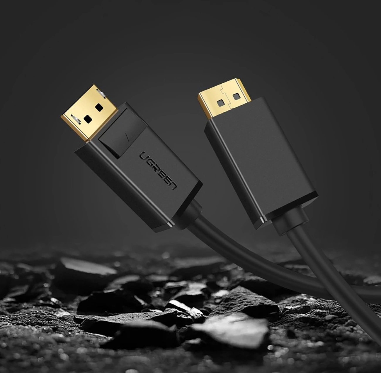 Dwa czarne kable DisplayPort UGREEN ze złotymi złączami. Tło jest ciemne i teksturowane, o skalistym wyglądzie.