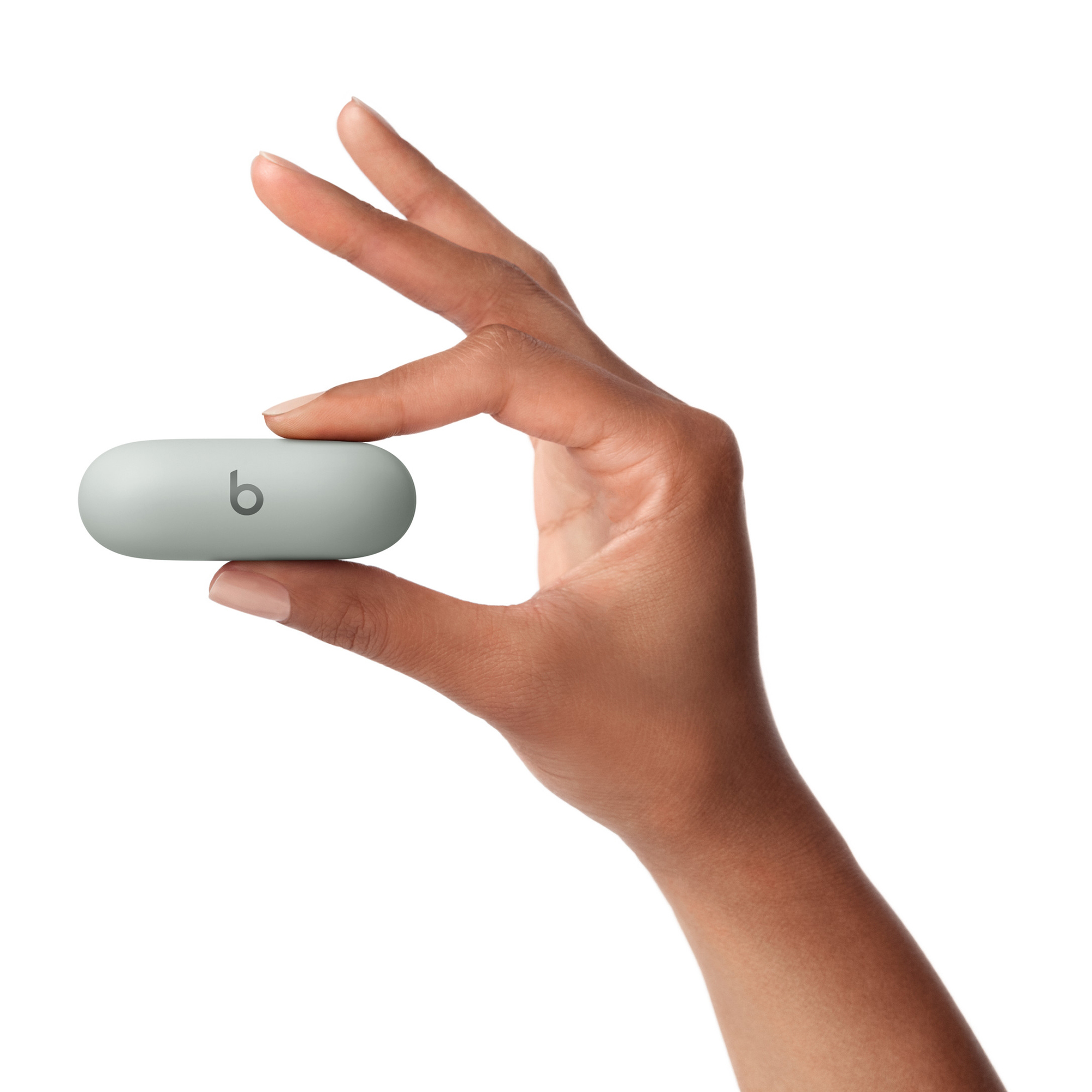 Dłoń trzyma szarą słuchawkę. Słuchawka ma logo 'b'. Tło jest białe.