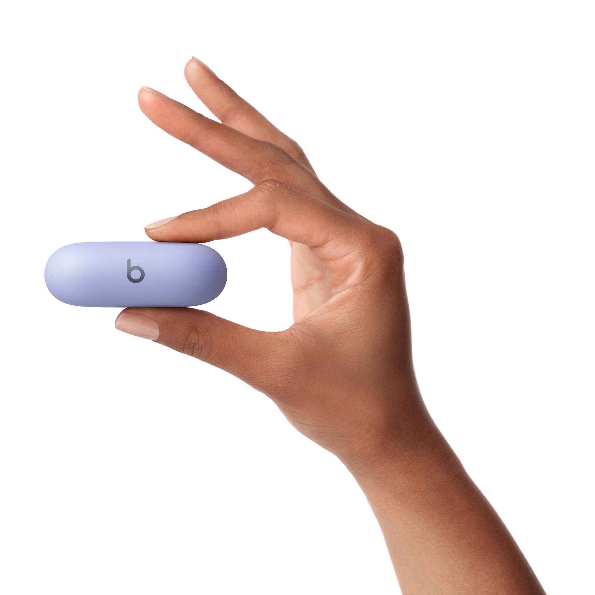 Dłoń trzyma jasno fioletową słuchawkę. Słuchawka ma czarne logo 'b'. Tło jest białe.