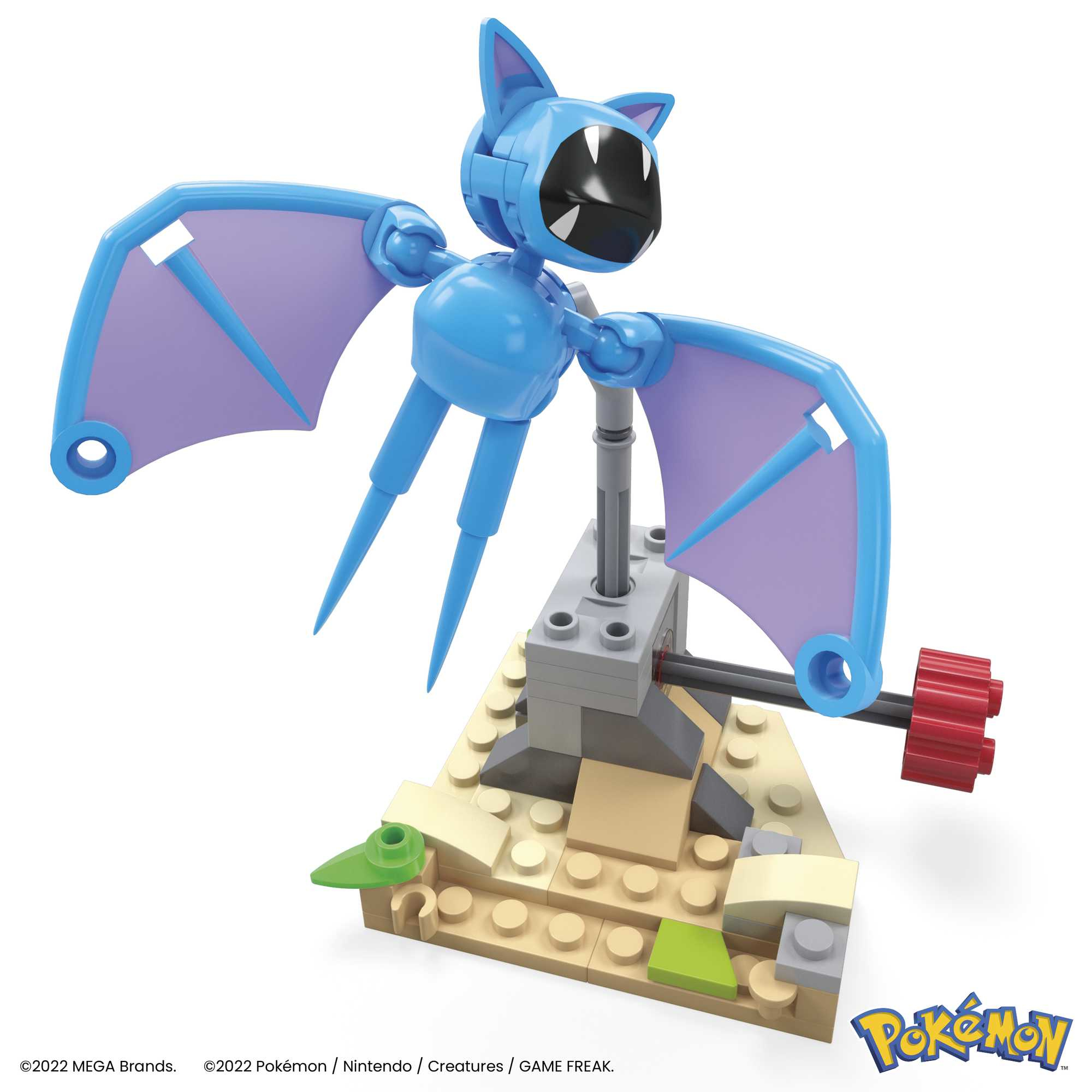 Niebieska figurka Lego Pokemon z fioletowymi skrzydłami, wspierana przez szarą konstrukcję na beżowej podstawie. Czerwone koło zębate z boku.