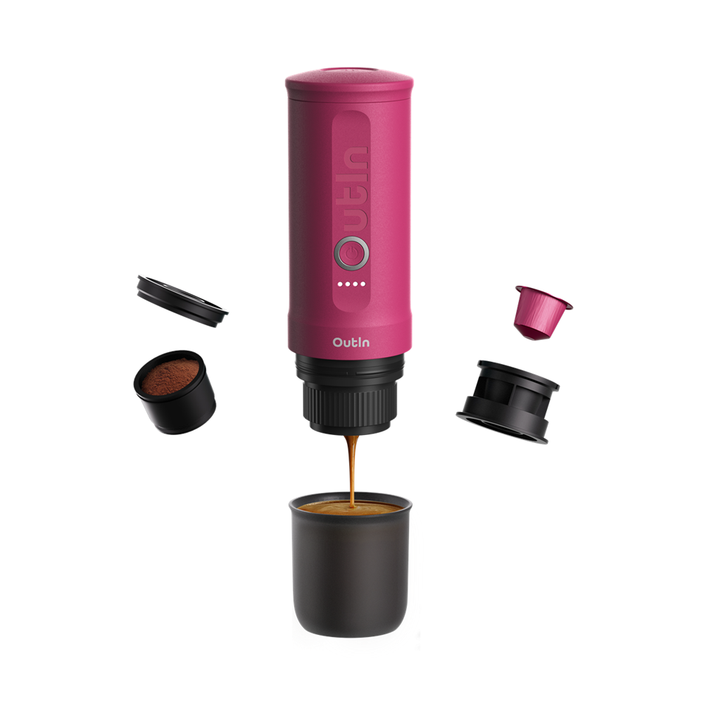 Magenta ekspres Outin wlewa kawę do czarnego kubka. Kapsułki z kawą i elementy są rozmieszczone wokół ekspresu.