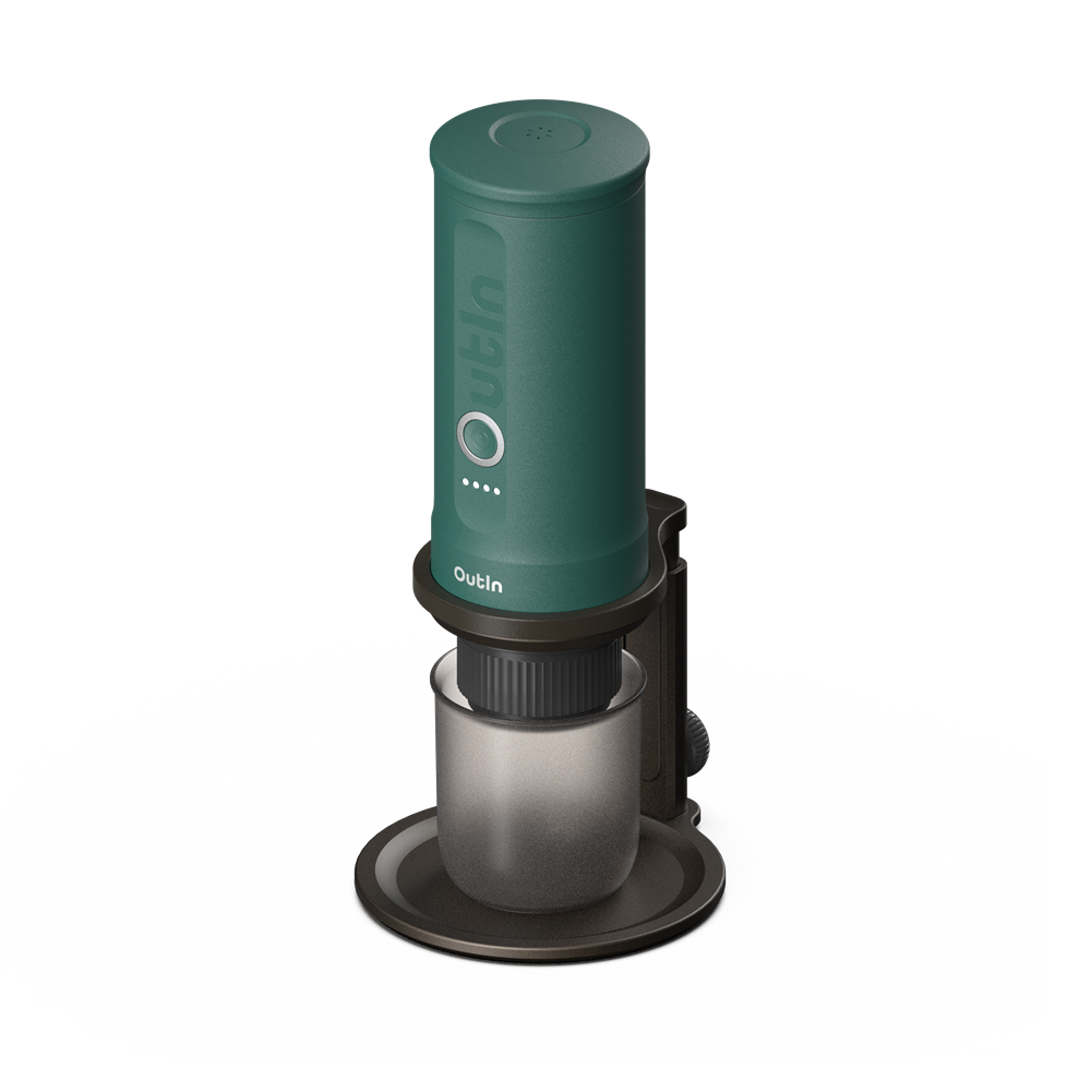 Zielone urządzenie Outin ze szklanym pojemnikiem. Znajduje się na ciemnobrązowej podstawie. Tło jest białe z czarnym gradientem.