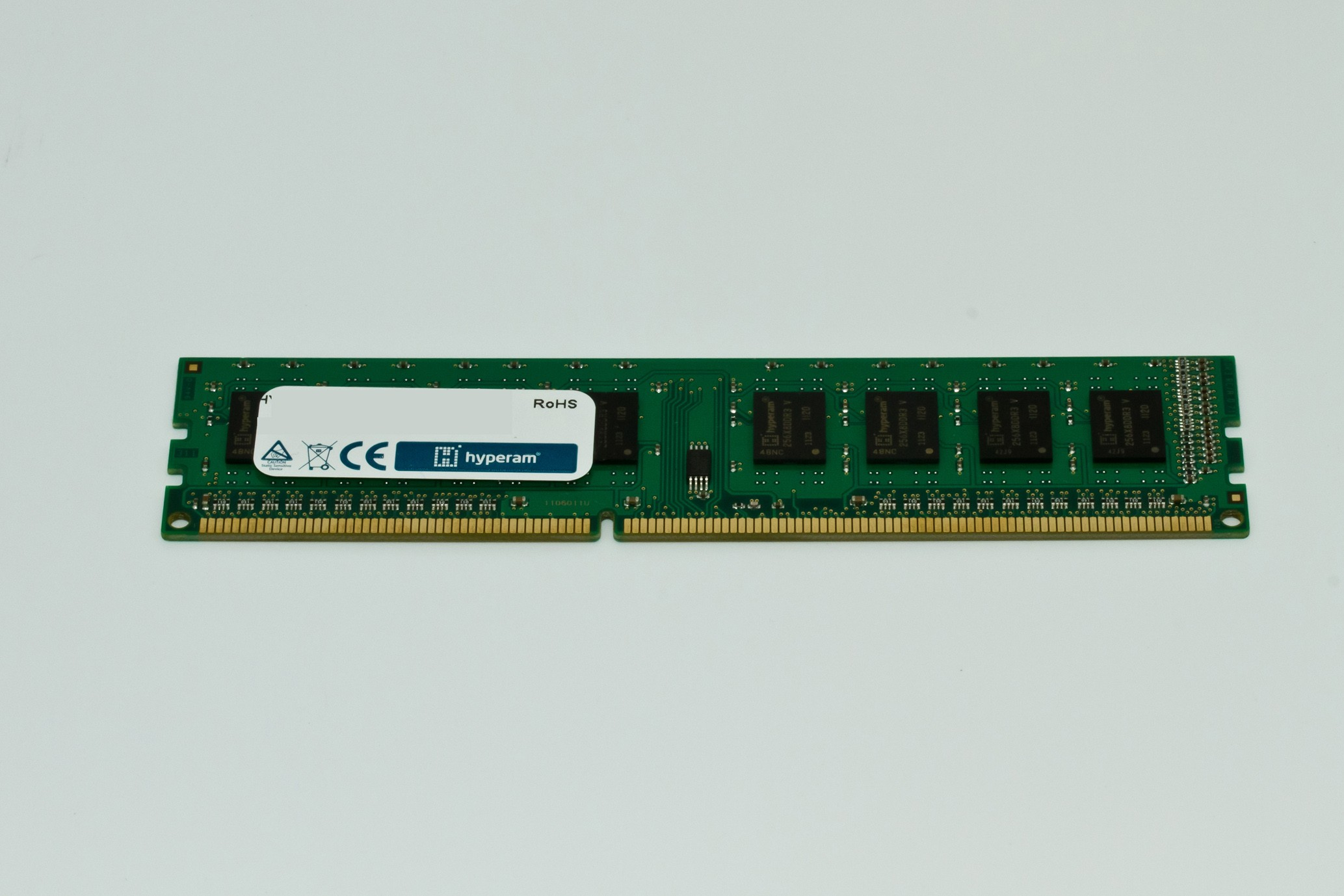 Un modulo RAM verde su una superficie bianca. Ha chip e connettori. Il marchio 'hyperam' è visibile. Marchi RoHS e CE presenti.