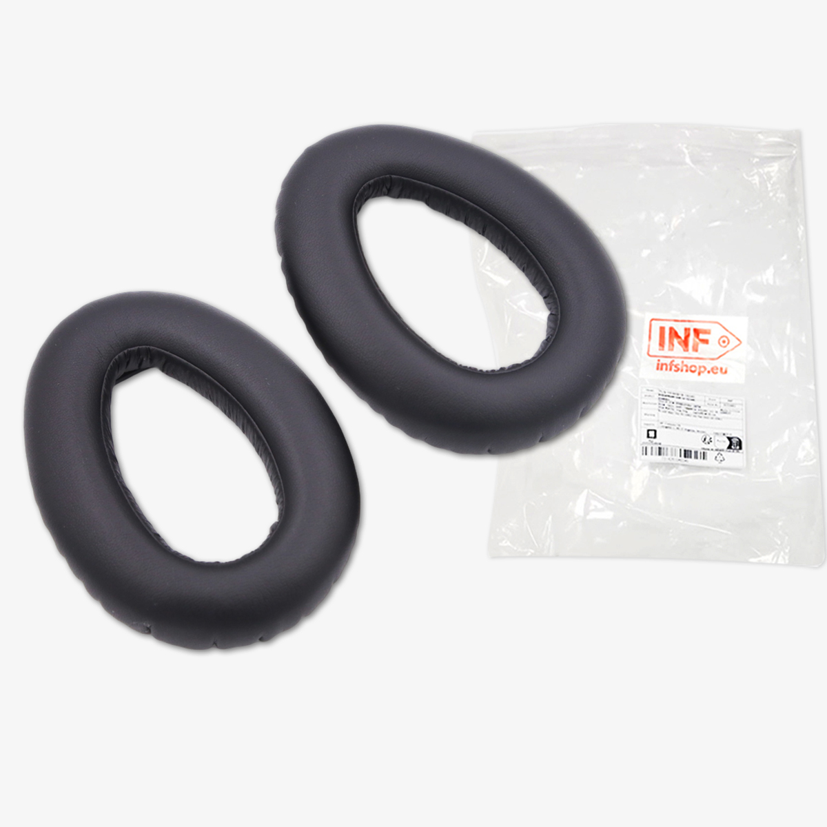 Dwie czarne, owalne nauszniki na białej powierzchni. Po prawej stronie przezroczysta plastikowa torba z etykietą.