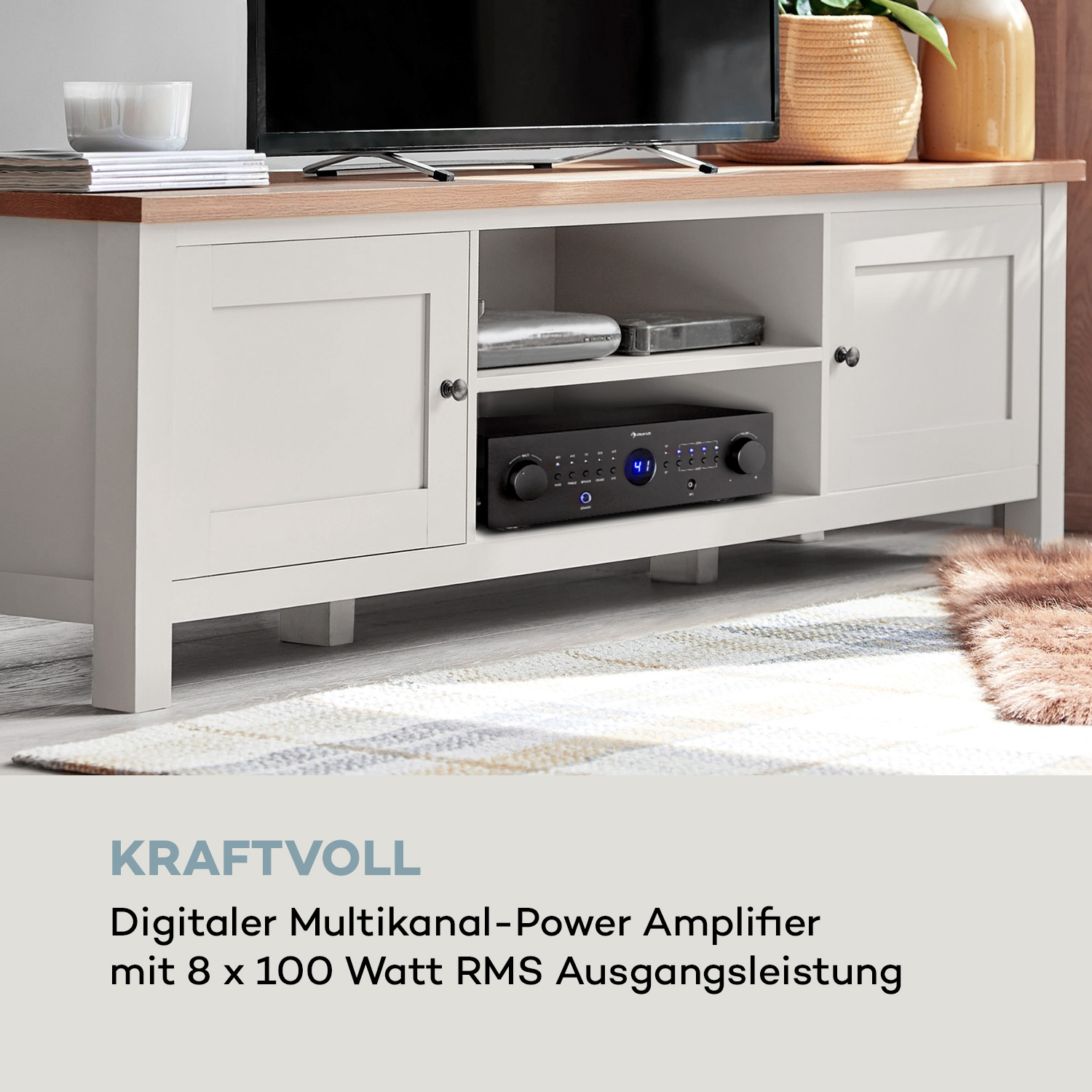 Ein weißer Schrank mit Fernseher. Ein schwarzer Verstärker ist innen. Auf dem Boden liegt ein Teppich. Der Schrank hat Türen.
