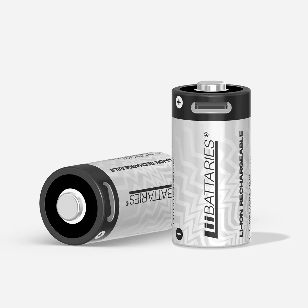 Dwa cylindryczne akumulatory Li-ion w czarno-srebrnym designie. Jeden stoi, drugi leży. Białe tło.