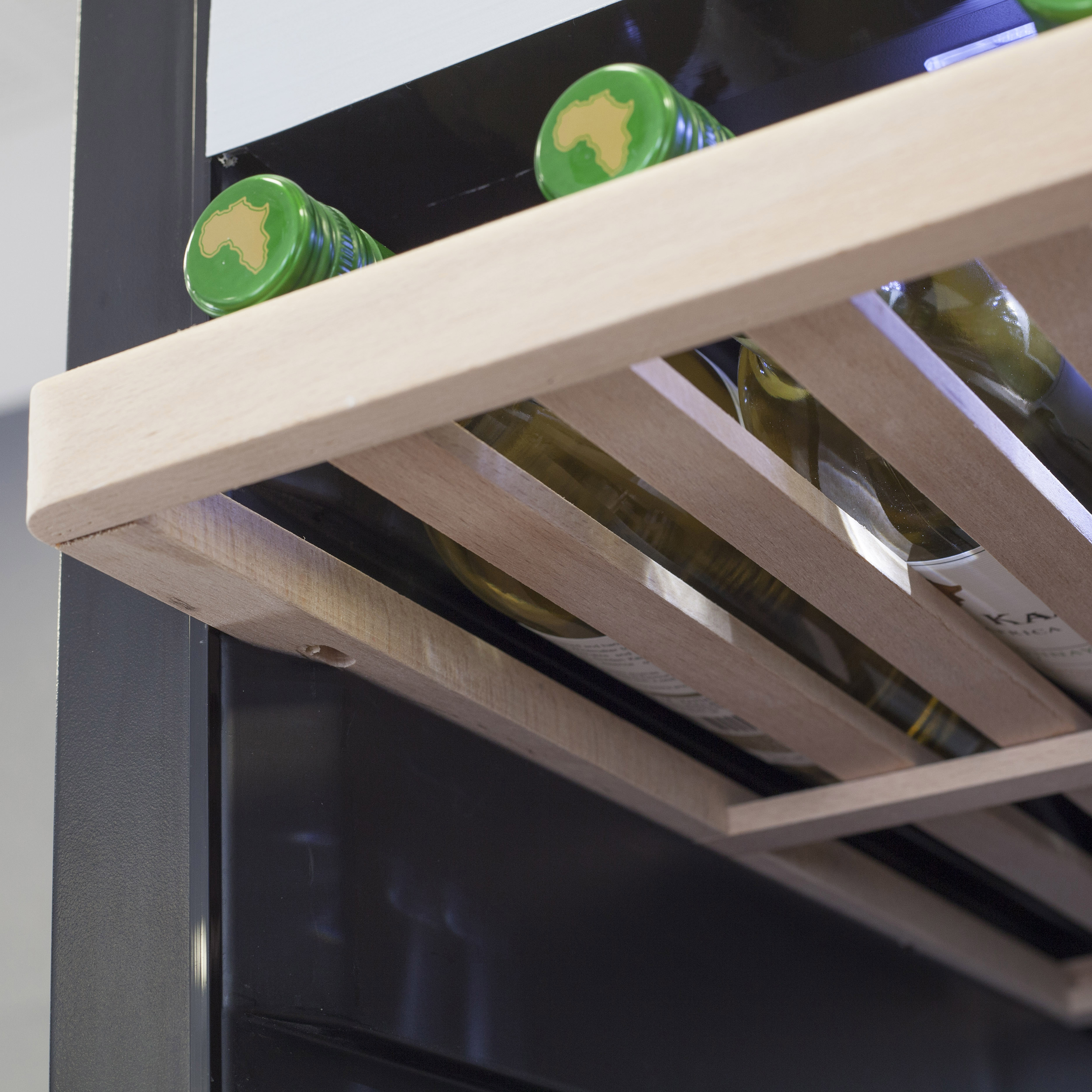 Wein wird in einem dunklen Kühler mit grünen Flaschenverschlüssen auf einem Holzregal gelagert.