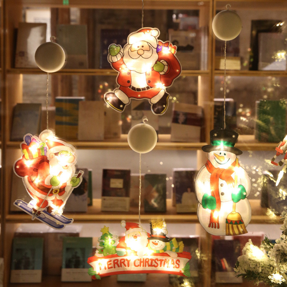 Weihnachtsdekorationen mit Weihnachtsmann, Schneemann und 'Merry Christmas'-Schild. Bücherregale im Hintergrund. Festlich und beleuchtet.