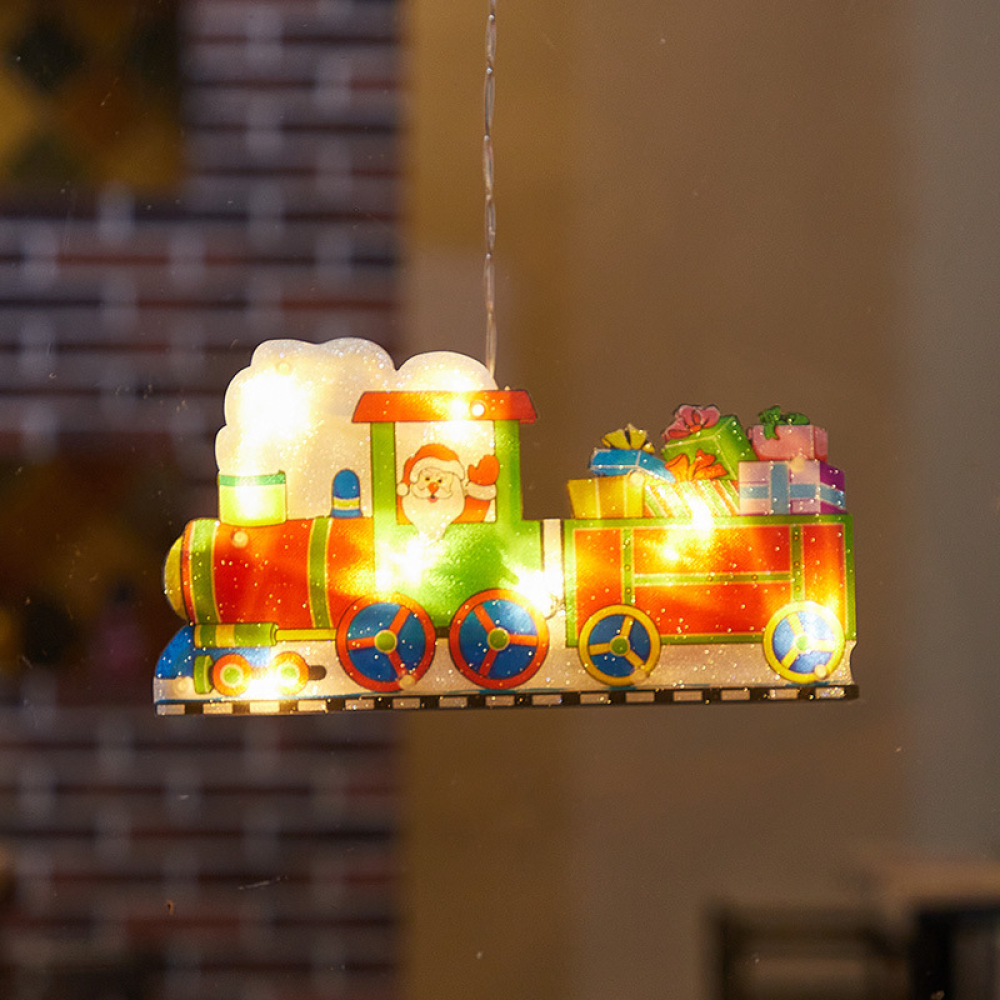 Eine Weihnachtsdekoration in Form eines Zuges mit Santa, Geschenken und bunten Lichtern. Sie hängt vor einem verschwommenen Hintergrund.
