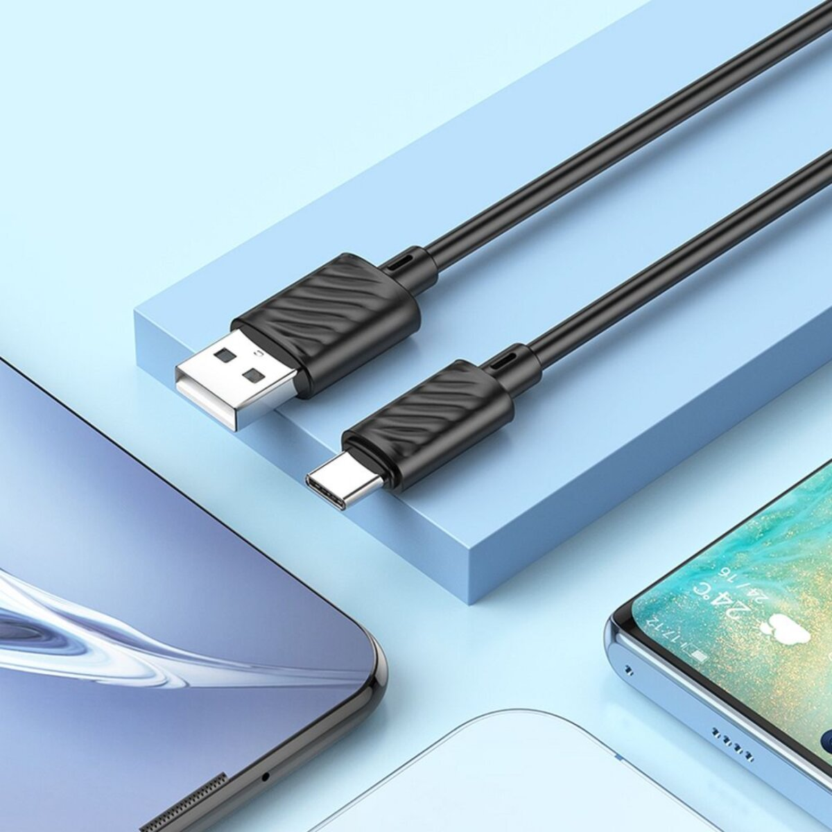 Due cavi USB neri con connettori USB-A e USB-C su una superficie blu, vicino a smartphone.