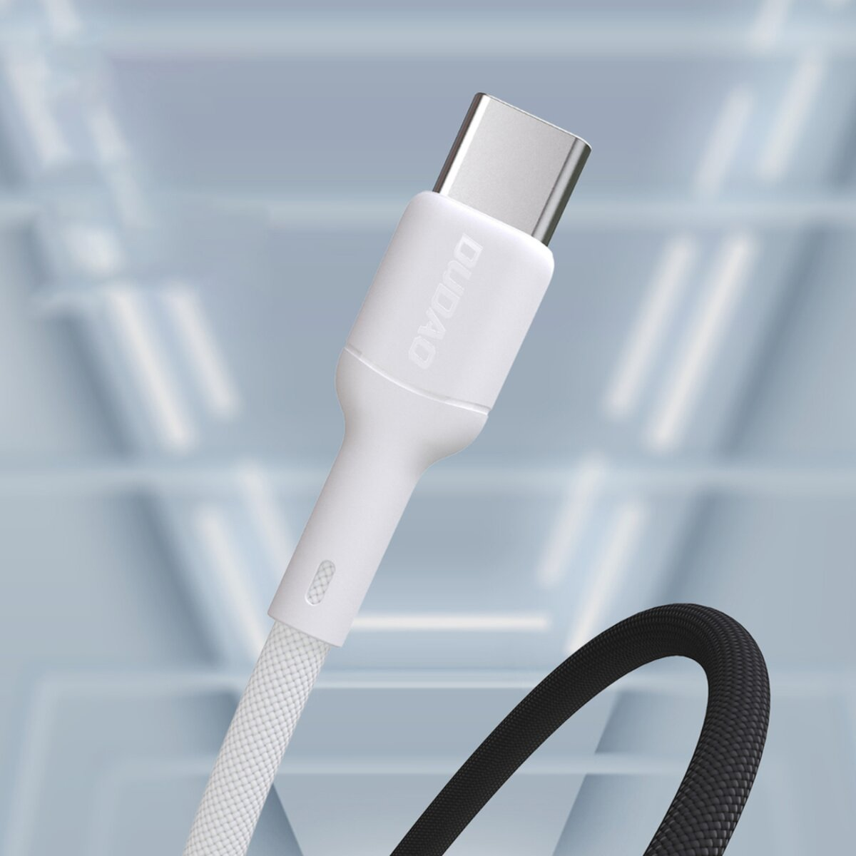 Ein weißes und silbernes USB-C-Kabel mit der Aufschrift 'DUDAO' und einem geflochtenen weißen Kabel. Im Hintergrund ein schwarzes Kabel.