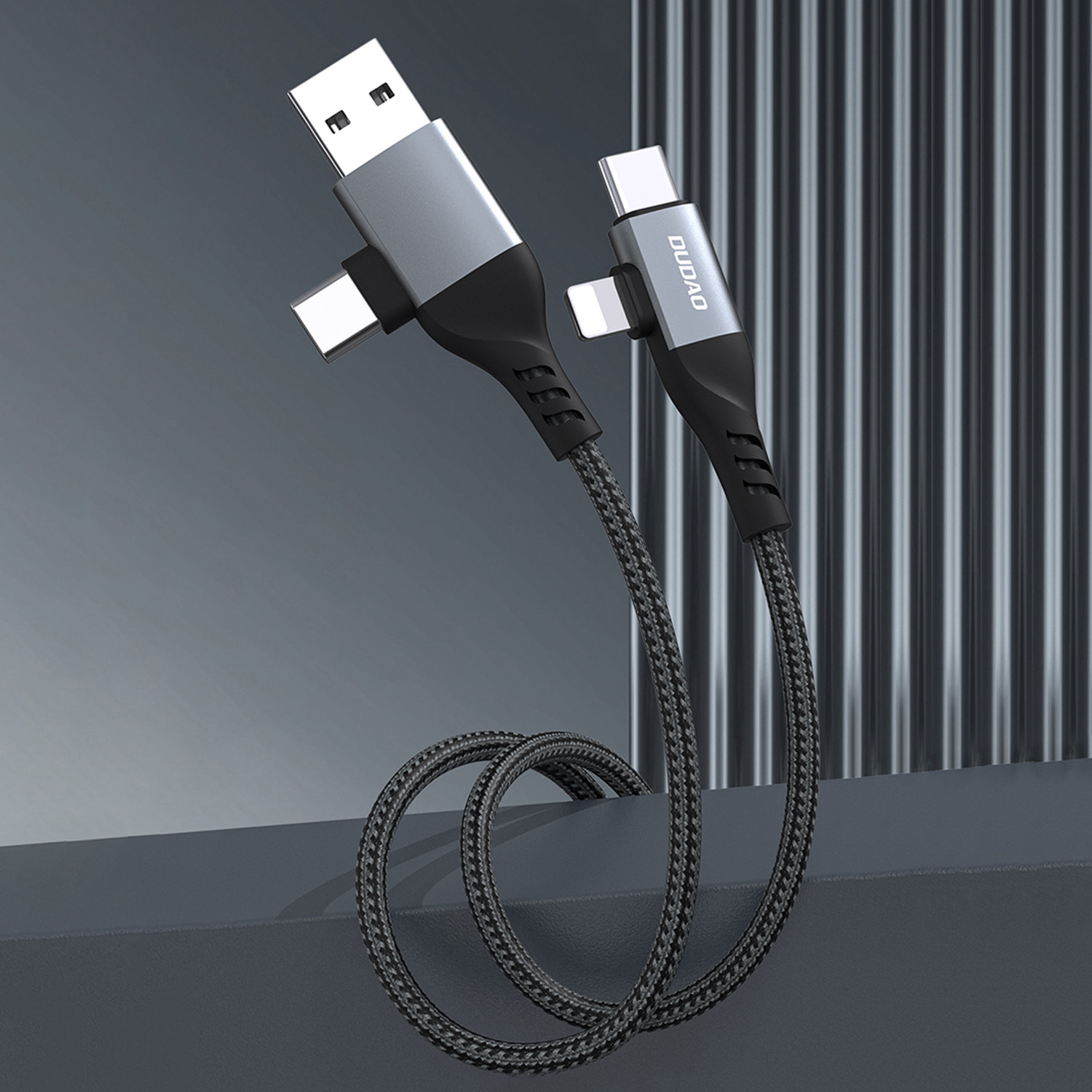 Ein schwarz-graues Ladekabel mit USB-, USB-C- und Lightning-Anschlüssen auf grauem Hintergrund.