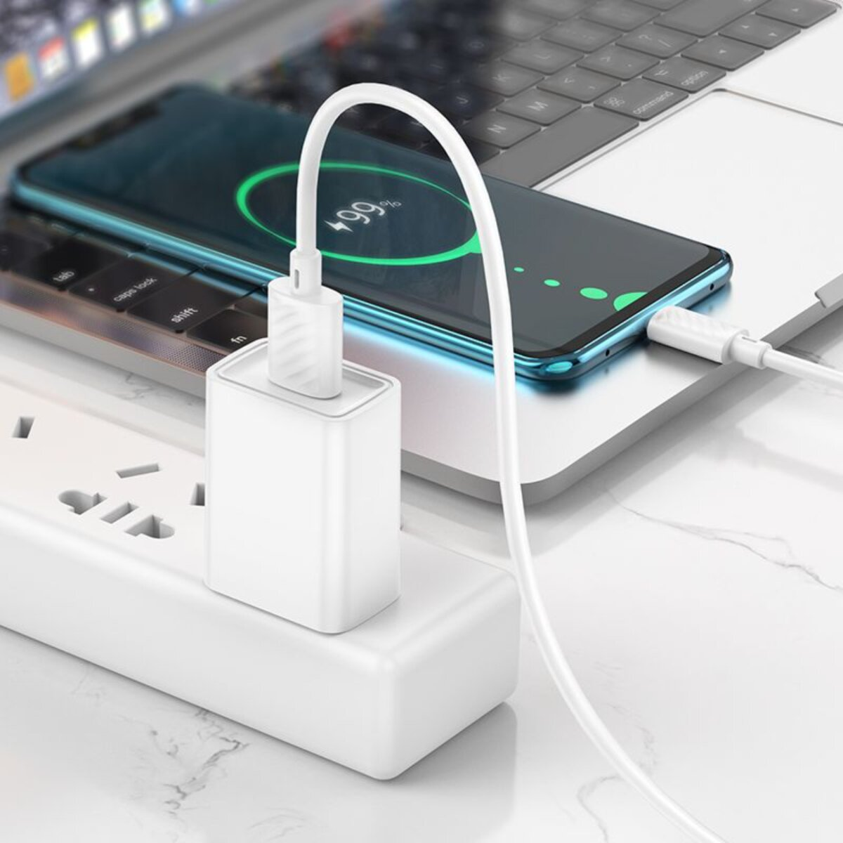 Ein weißes Telefonladegerät, das in eine Steckdosenleiste eingesteckt ist. Ein Telefon lädt auf einem Laptop und zeigt 99% geladen an.