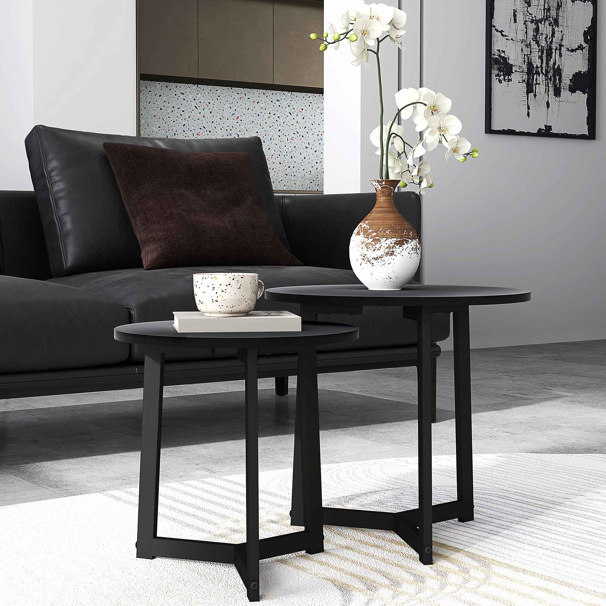 Wohnzimmerszene mit schwarzem Sofa, zwei schwarzen Tischen, einer Vase mit Blumen und einem Gemälde an der Wand.