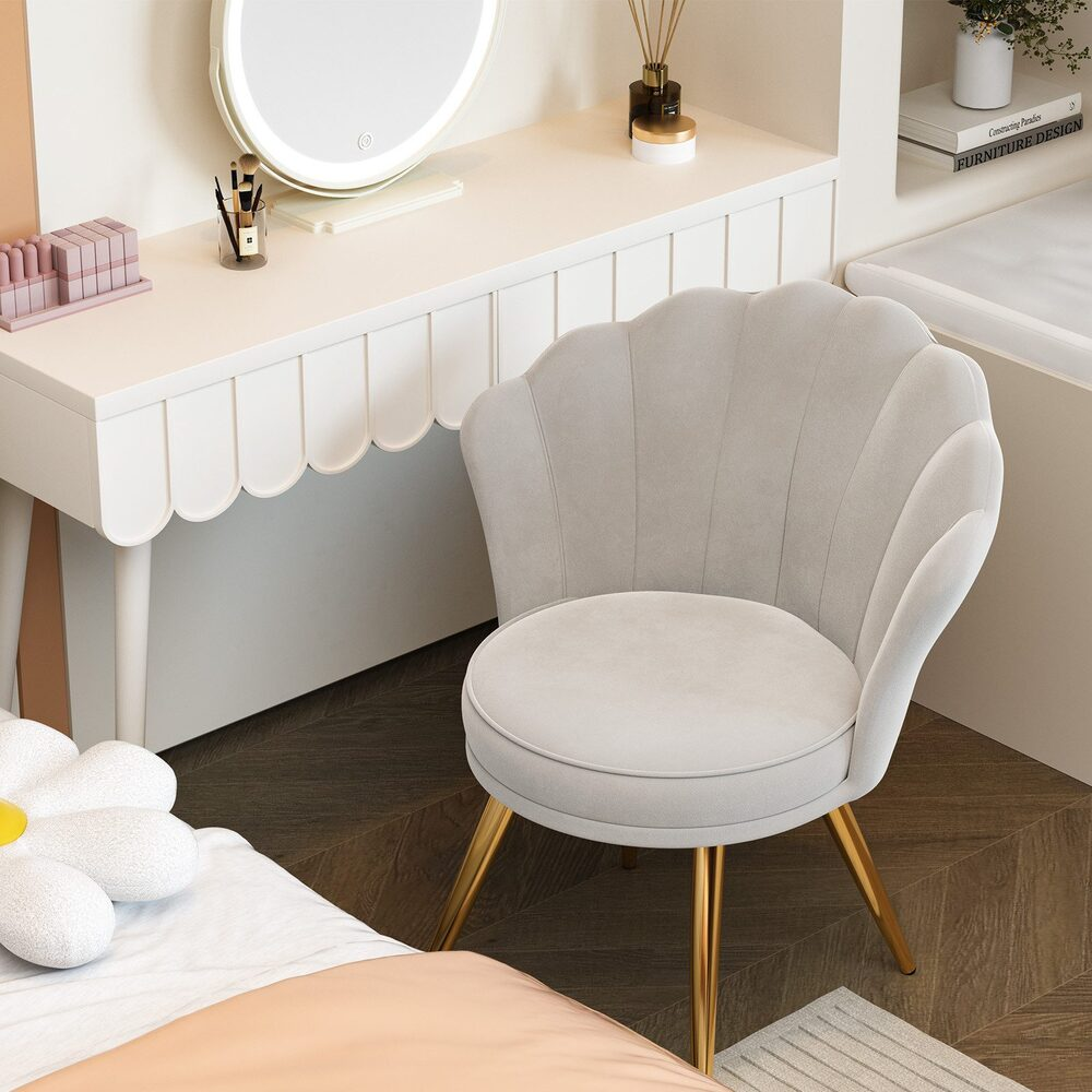 Ein Schminkbereich mit einem weißen Tisch mit Muschelrändern, einem muschelförmigen Stuhl und einem großen Spiegel. Ein Bett mit einem blütenförmigen Kissen.