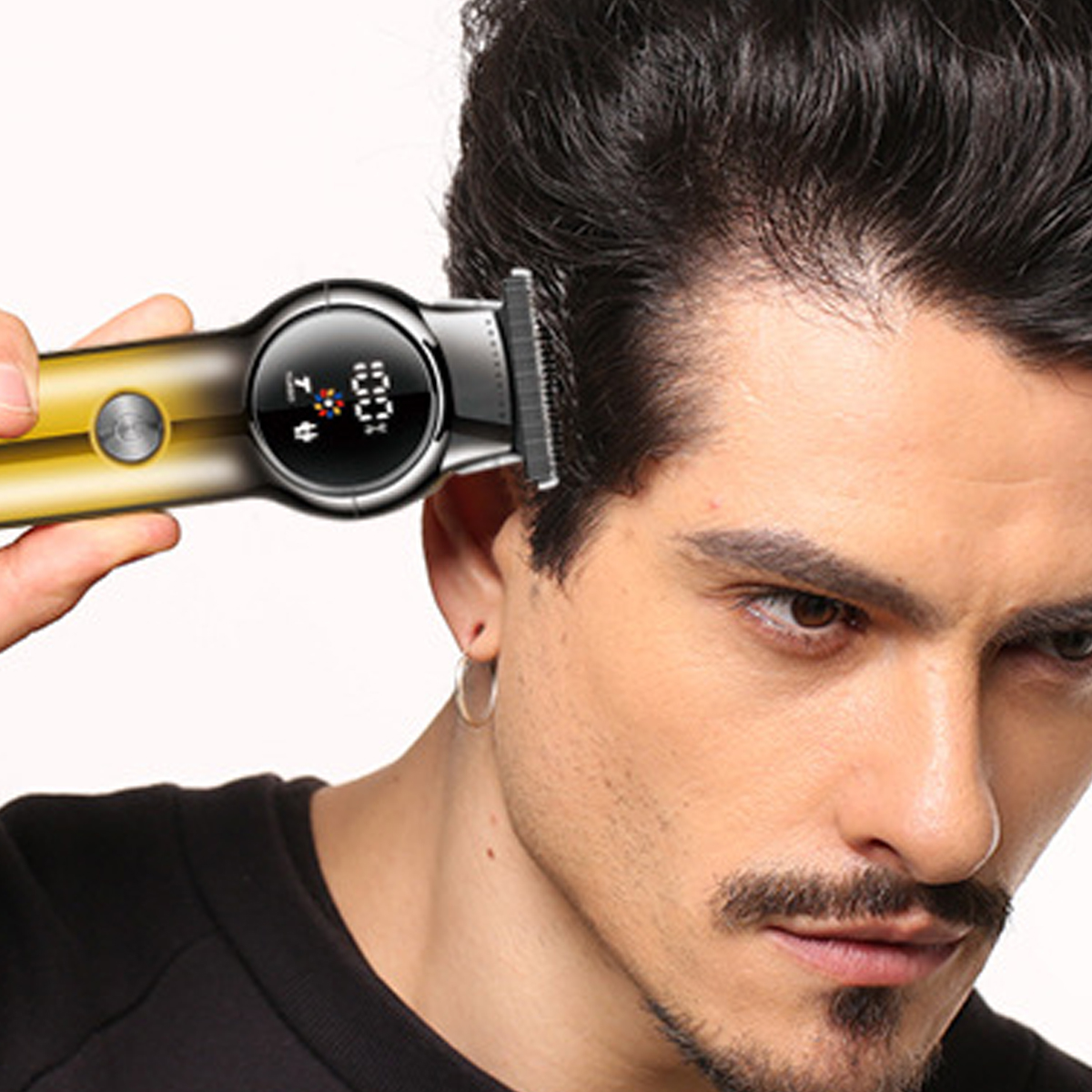 Ein Mann benutzt einen Haarschneider. Der Clipper wird in der Nähe des Ohrs des Mannes gehalten, das Display zeigt 100%. Der Mann schaut in die Kamera.
