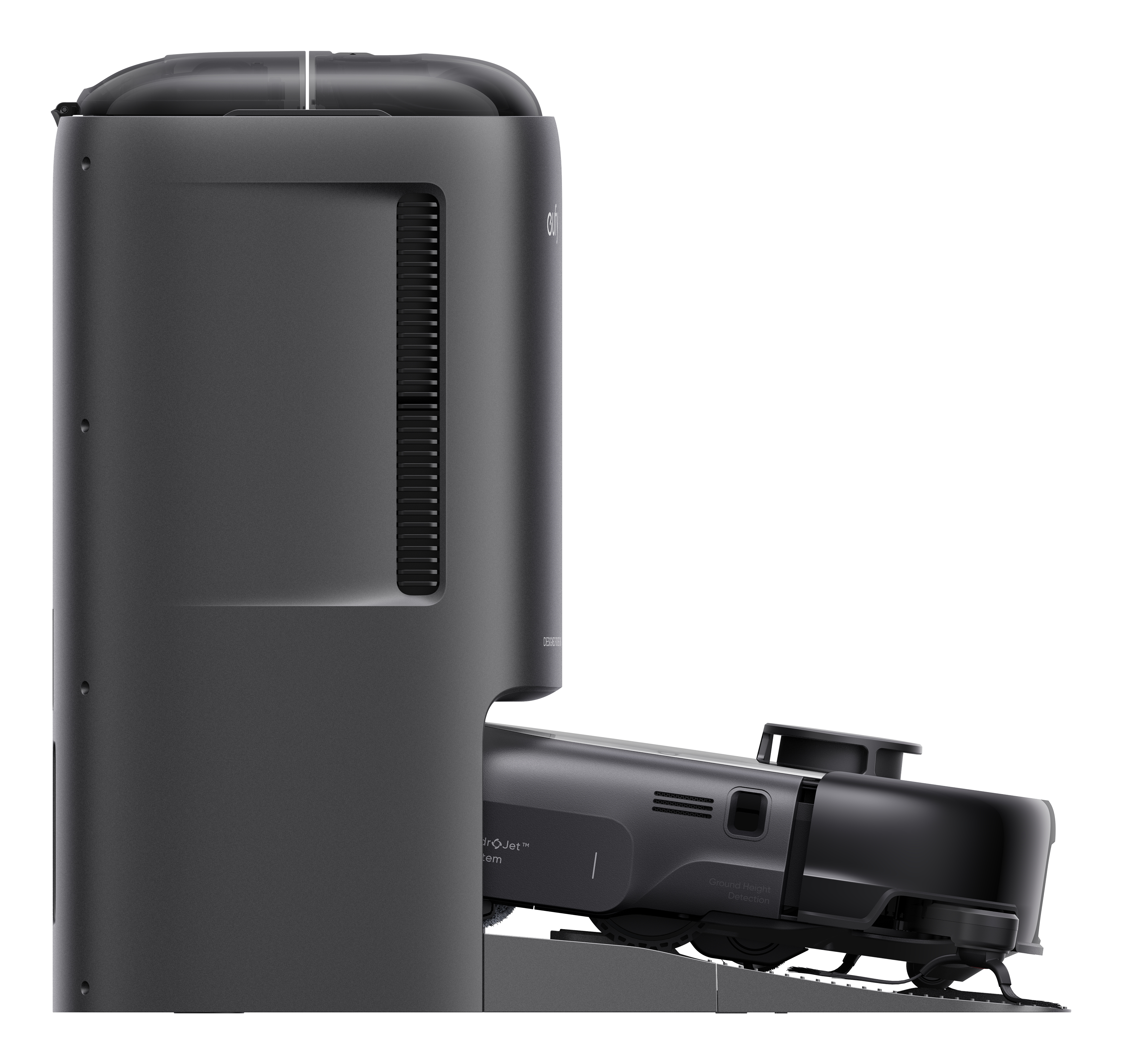 Ciemnoszary robot odkurzający zadokowany w stacji ładującej. Stacja ma wysoki, cylindryczny kształt.