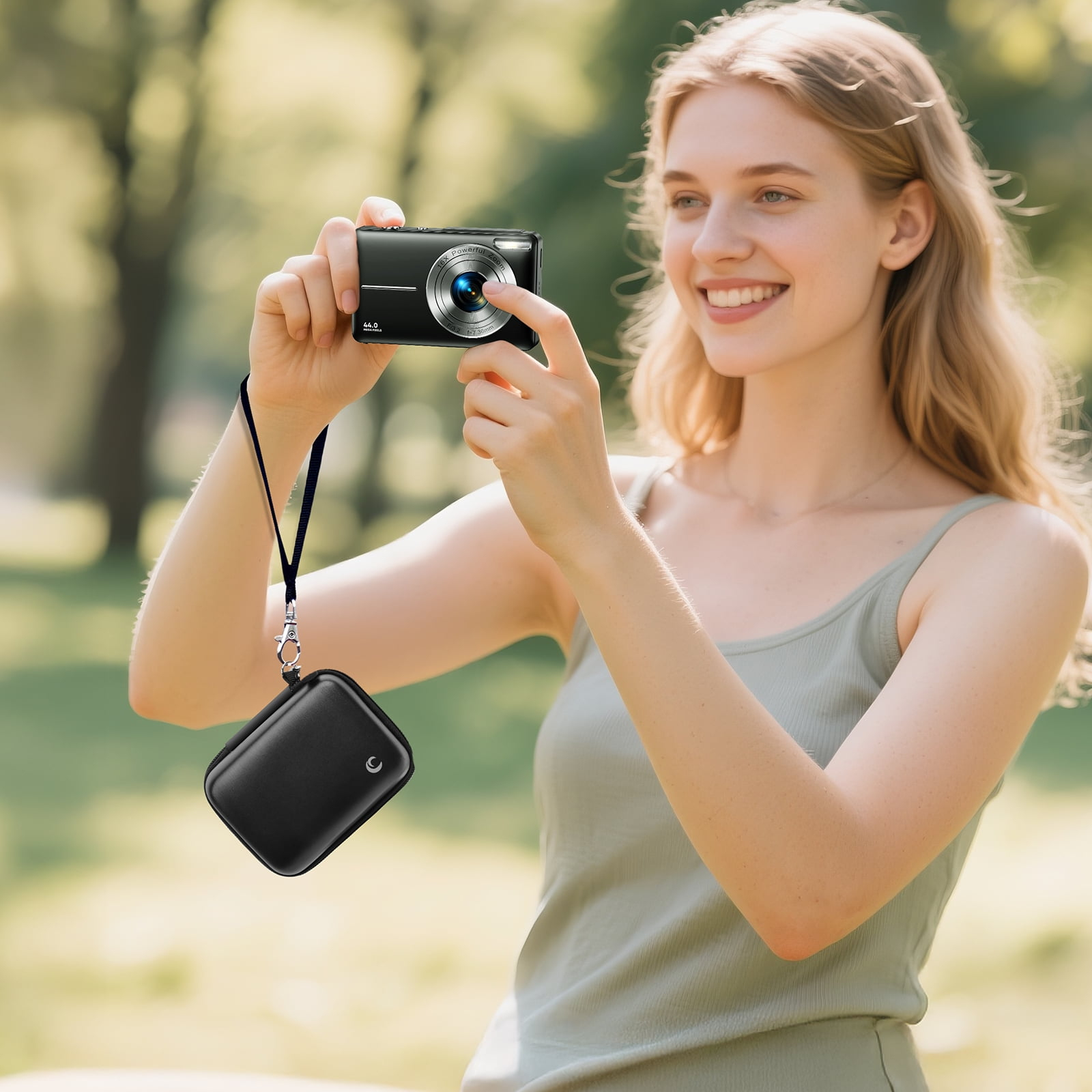 Blonde Frau macht ein Foto mit einer schwarzen Kamera. Eine schwarze Hülle hängt an ihrem Handgelenk. Grüner Hintergrund.