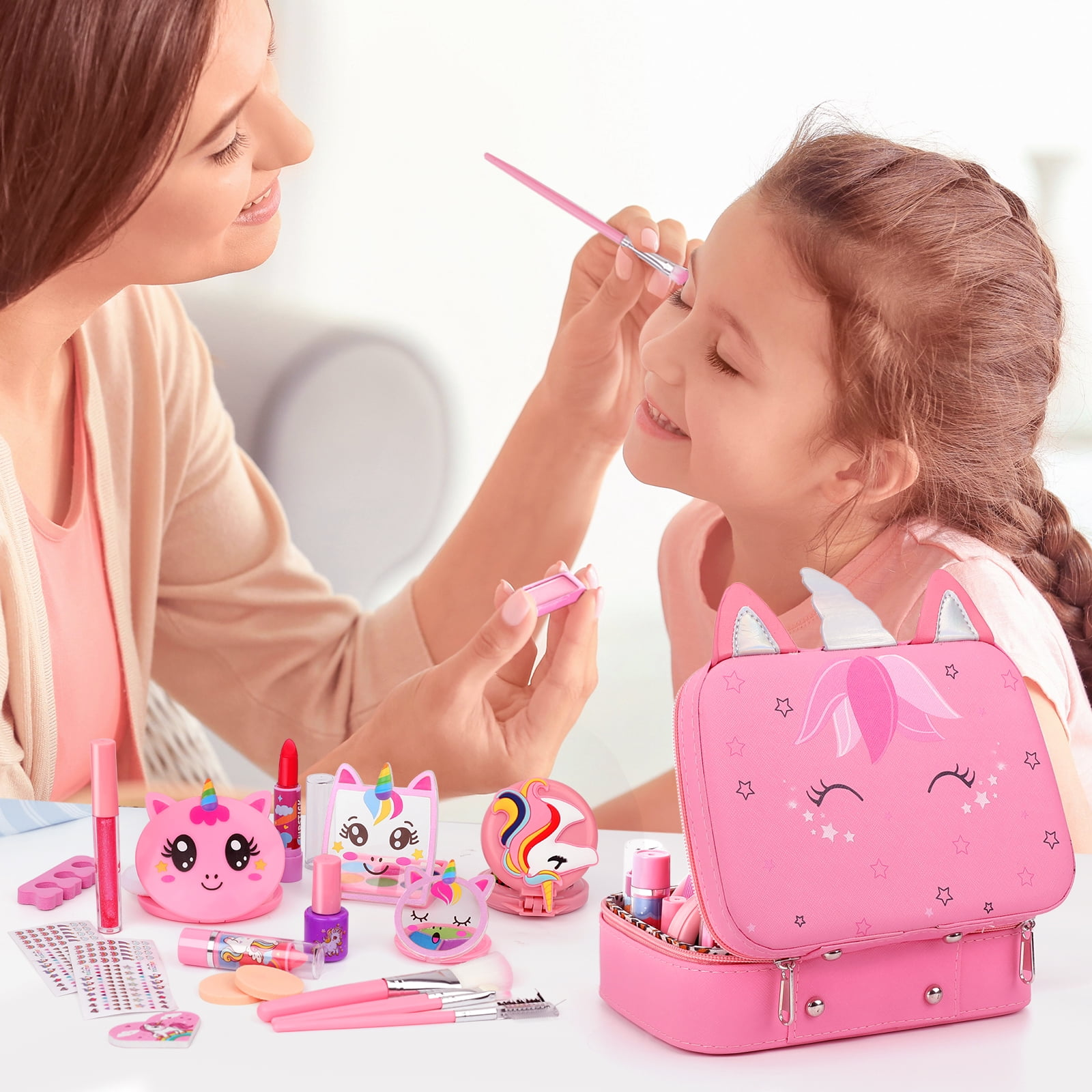 Eine Frau schminkt ein Mädchen. Auf dem Tisch befindet sich ein Make-up-Set mit Einhorn-Design. Das Set ist rosa.