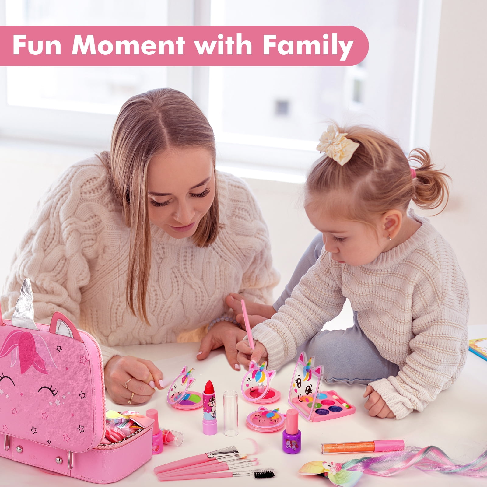 Eine Frau und ein Mädchen spielen mit Make-up. Ein pinkfarbenes Einhorn-Make-up-Set und Zubehör liegen auf dem Tisch. Ein lustiger Familienmoment.