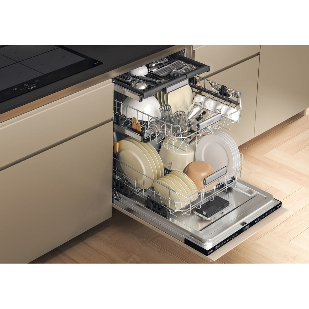 Open dishwasher filled with plates, glasses, and utensils. Beige kitchen cabinets and a black stovetop are visible in the background.
