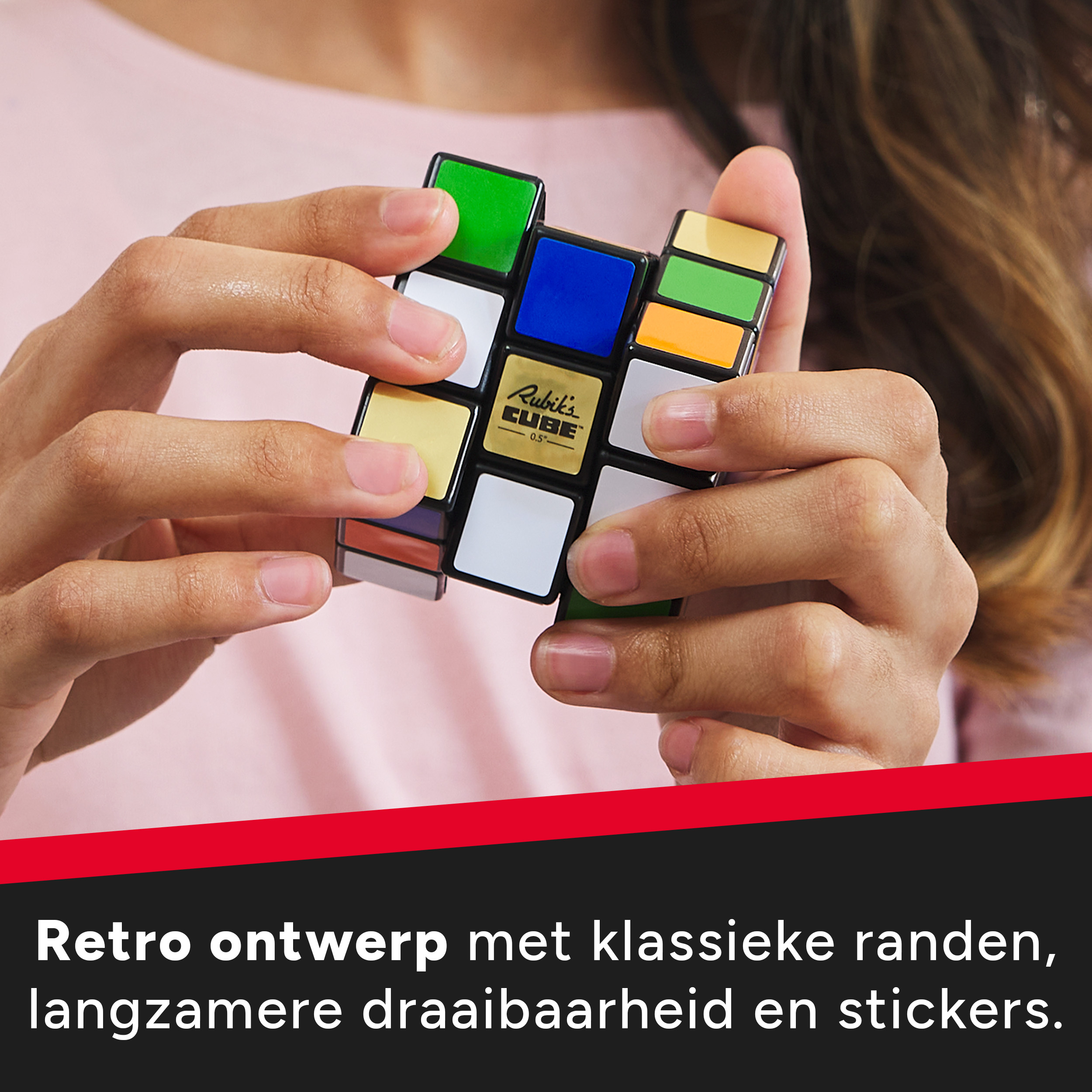 Una persona tiene in mano un Cubo di Rubik. Il cubo ha quadrati colorati. Lo sfondo è una camicia rosa.