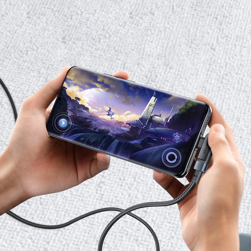 Ein Telefon, das eine Spielszene anzeigt, ist mit einem Ladekabel verbunden. Hände halten das Telefon. Der Hintergrund ist weich und hell.
