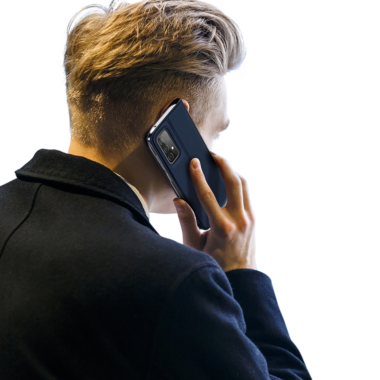 Un uomo tiene un telefono all'orecchio. Indossa un cappotto scuro e ha i capelli biondi. Il telefono è blu scuro.