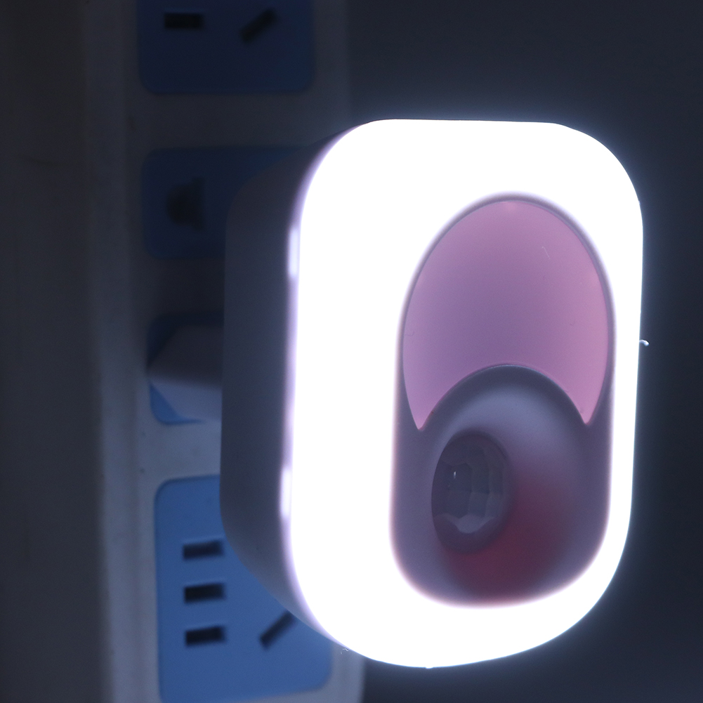 Ein Nachtlicht steckt in einer Steckdose. Das Licht ist weiß und hat einen rosa-violetten Innenraum. Die Steckdose ist weiß und blau.