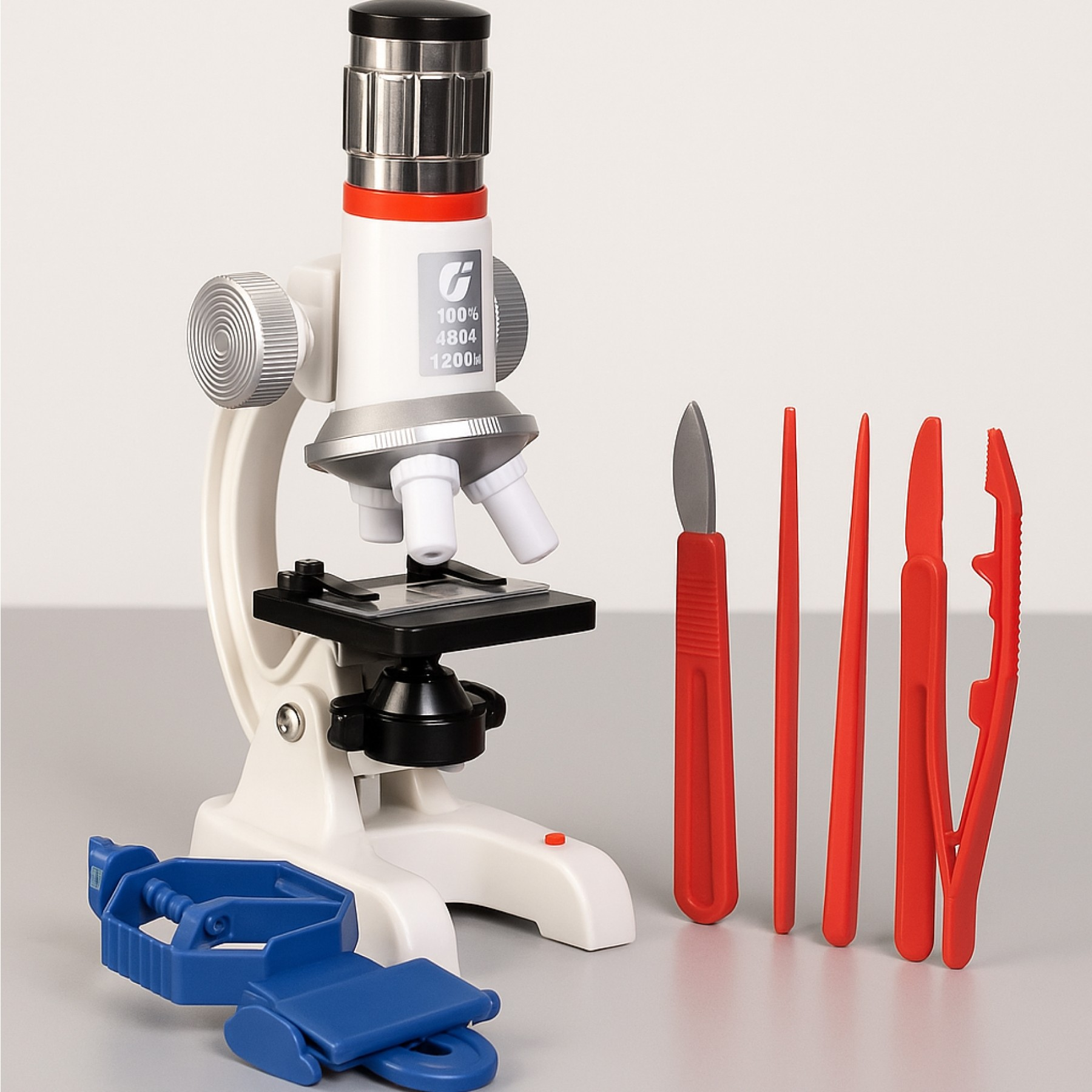 Biały mikroskop ze srebrnymi akcentami i czerwonymi narzędziami. Niebieski stojak z przodu. Tło jest szare.