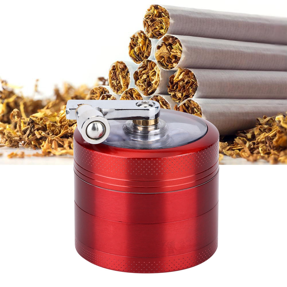 Ein roter Grinder mit silbernem Griff. Zigaretten und Tabak befinden sich im Hintergrund.