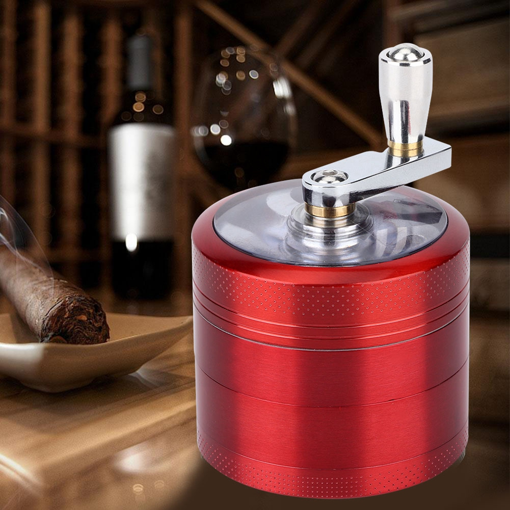 Ein roter Grinder mit silbernem Griff. Eine Zigarre liegt in einer kleinen weißen Schale, im Hintergrund eine Weinflasche und ein Glas.