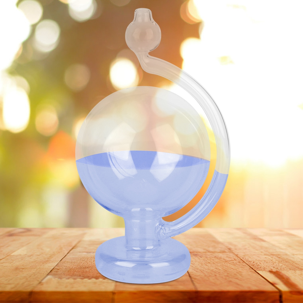 Eine klare Glaskugel, gefüllt mit blauer Flüssigkeit, steht auf einer Holzoberfläche. Der Hintergrund ist ein verschwommenes Bokeh.
