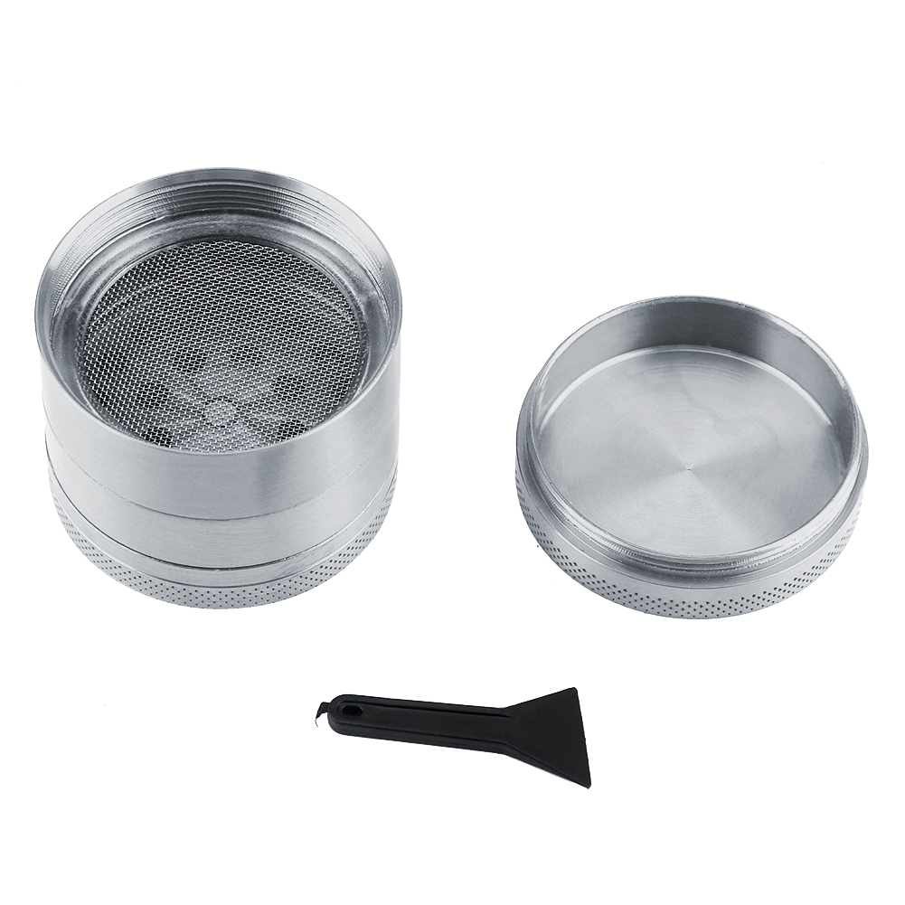 Offener silberner Grinder mit Sieb, Deckel und schwarzem Schaber auf weißem Hintergrund. Perforierte Seiten.