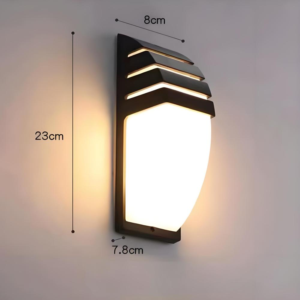 Eine schwarze Wandleuchte mit weißem, leuchtendem Licht. Maße: 23 cm hoch, 8 cm breit und 7,8 cm tief. An einer hellgrauen Wand montiert.