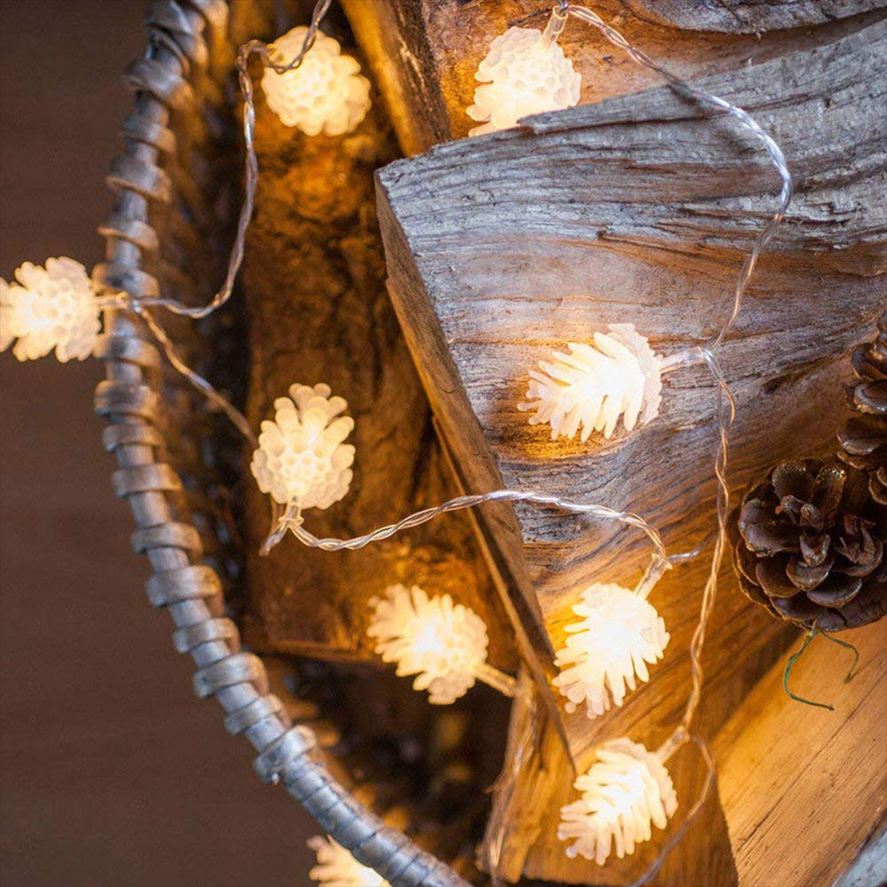 Lichterkette mit Tannenzapfen-Formen auf Holz und einem geflochtenen Korb. Die Lichter leuchten. Rechts ist ein Tannenzapfen.