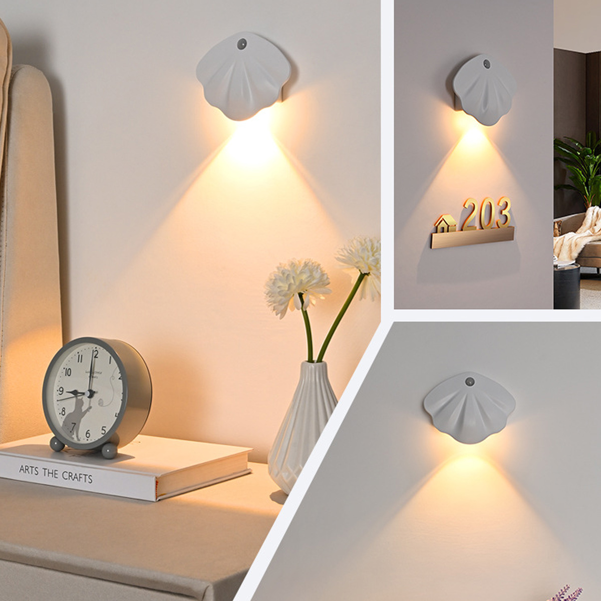 Eine weiße muschelförmige Lampe leuchtet an einer Wand. Eine Vase mit weißen Blumen steht auf einem Tisch mit Uhr und Buch.