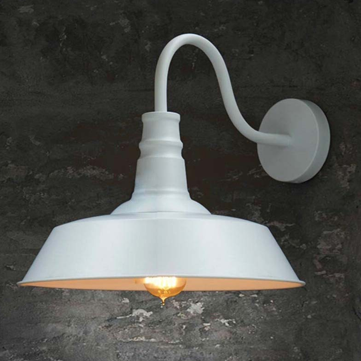 Eine weiße Außenlampe im Retro-Stil ist an einer strukturierten, grauen Backsteinmauer befestigt. Die leuchtende Glühbirne ist sichtbar.