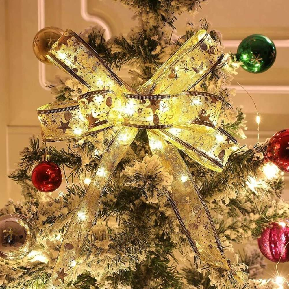 Ein geschmückter Weihnachtsbaum mit goldener Schleife, Ornamenten und Lichtern. Der Baum hat einen Schneeeffekt.