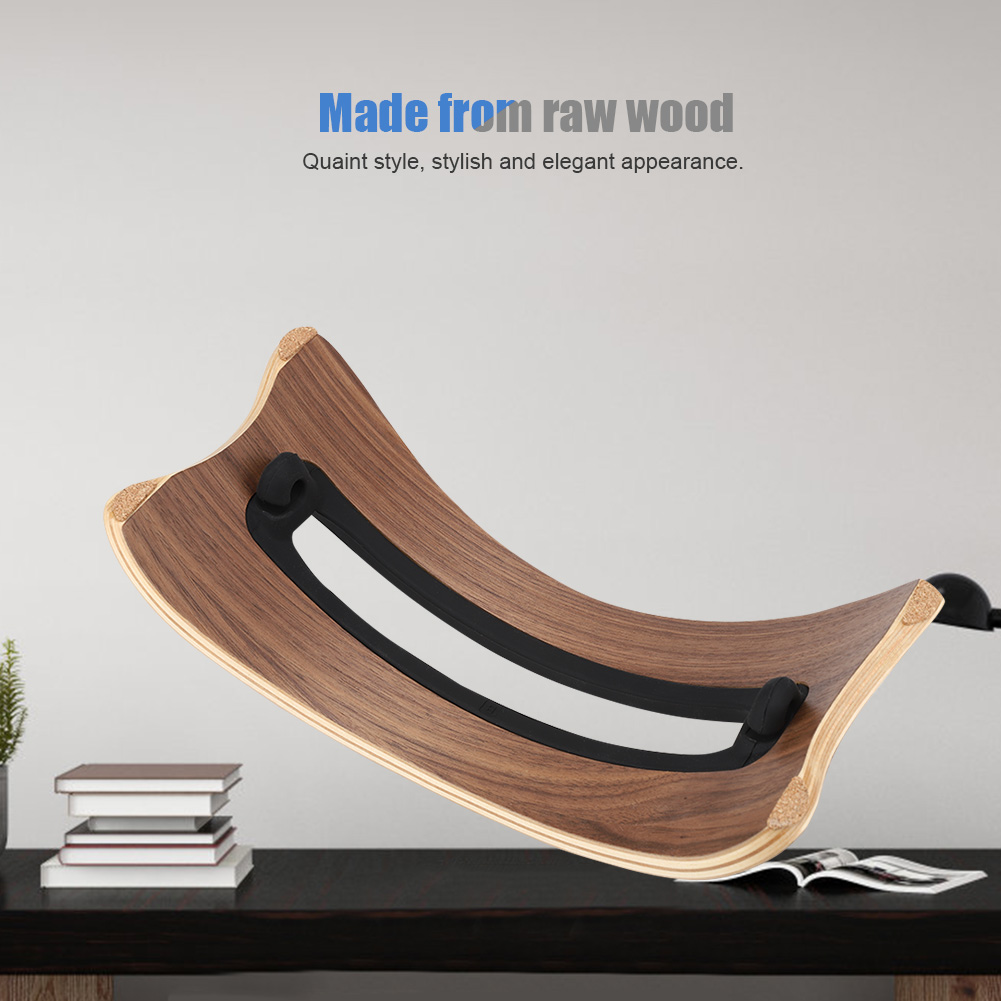 Ein Laptop-Ständer aus Holz mit geschwungenem Design. Er steht auf einem schwarzen Tisch mit Büchern und einer Zeitschrift.
