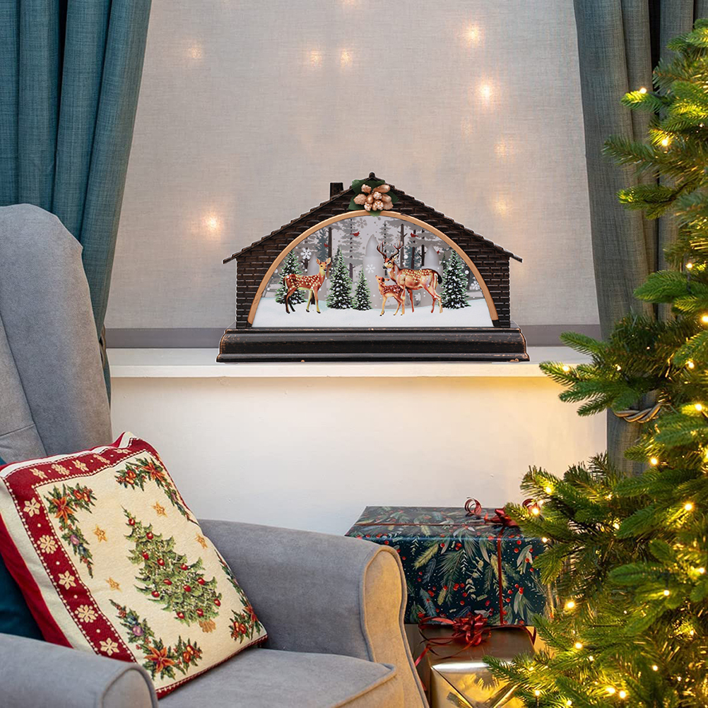 Eine Weihnachtsszene mit einem dekorativen Haus, Hirschen, einem Weihnachtsbaum, einem Kissen und einem Geschenk.