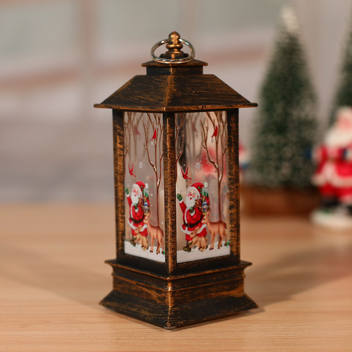 Eine dekorative Weihnachtslaterne mit Bildern von Santa Claus und Rentieren. Sie steht auf einer Holzoberfläche.