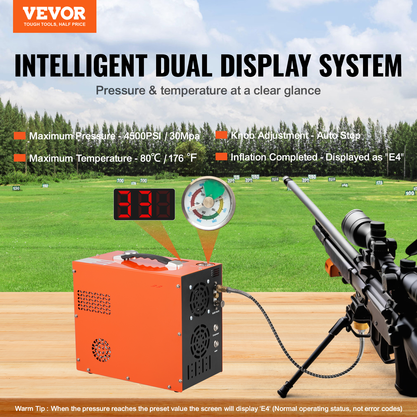 Ein orangefarbener Luftkompressor mit Manometer und Digitalanzeige. Im Hintergrund ein Gewehr auf einem grünen Feld.