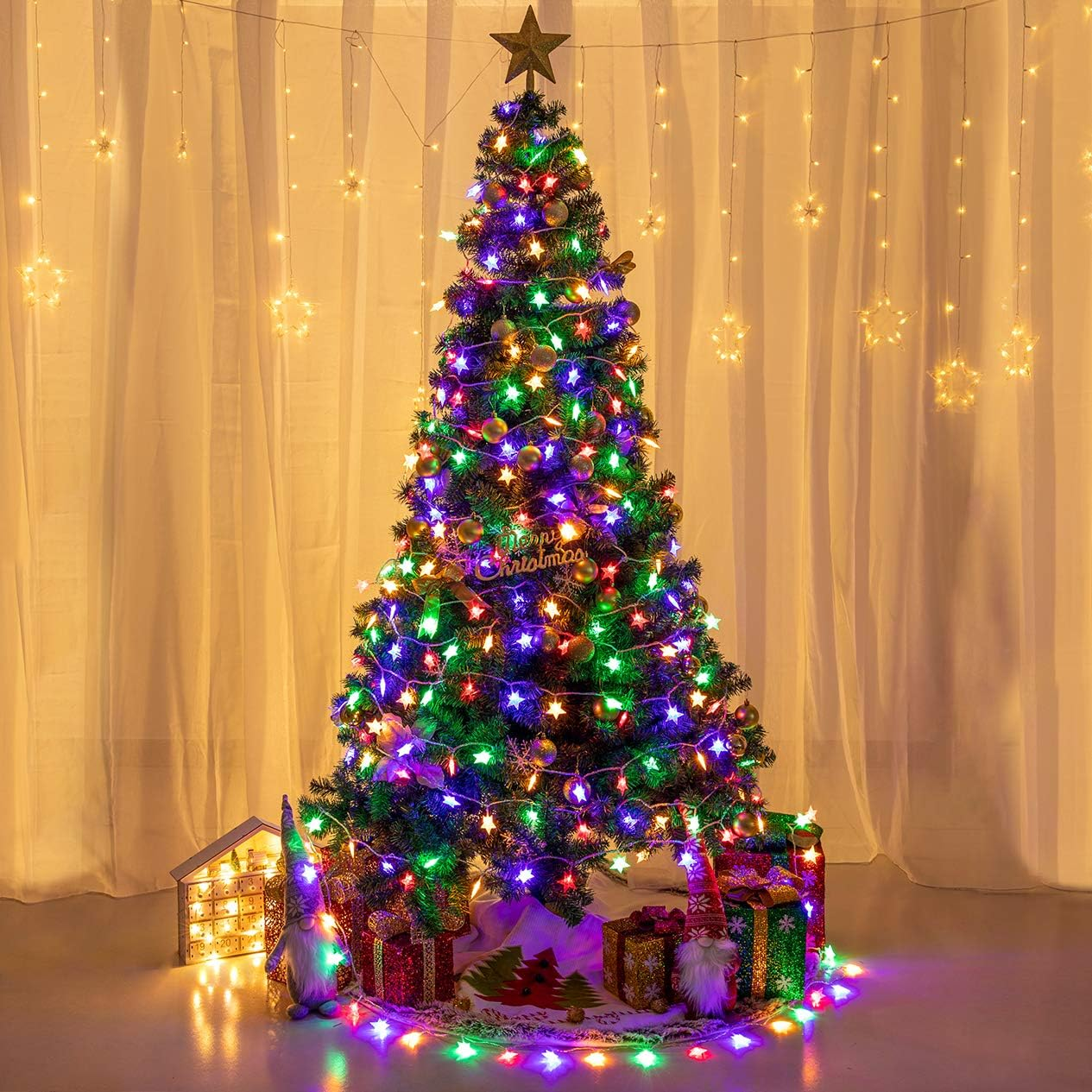 Ein geschmückter Weihnachtsbaum mit bunten Lichtern, Sternaufsatz und Geschenken. Der Hintergrund hat Vorhänge und sternförmige Lichter.